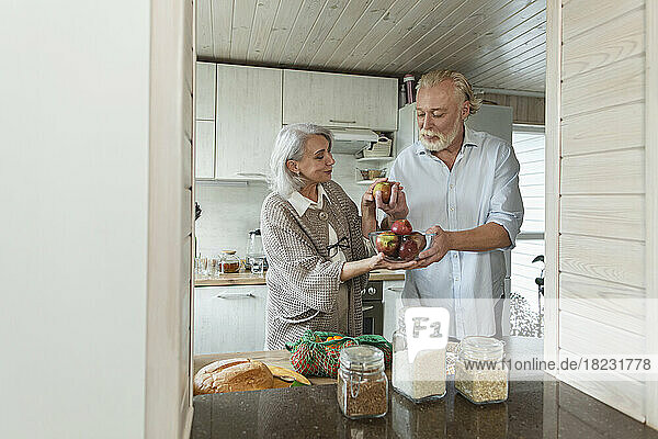 Senior couple holding fresh apples in kitchen