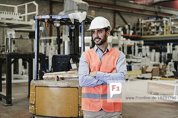 Smiling engineer wearing hardhat standing in industry