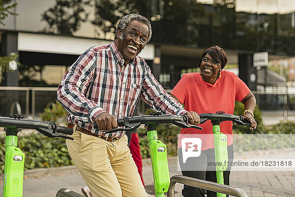 Cheerful senior couple enjoying with each other holding push scooters