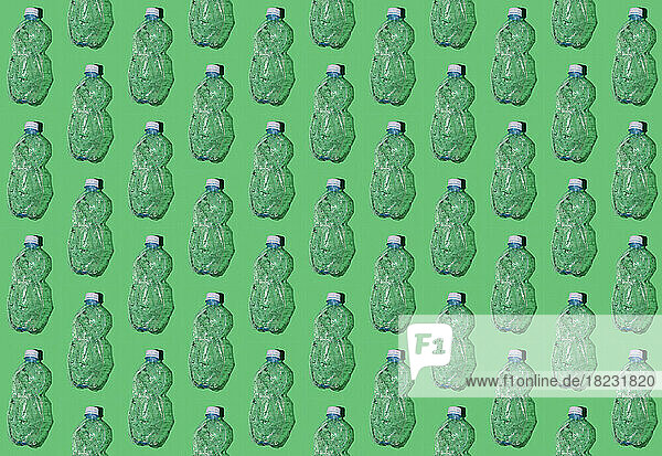 Pattern of rows of empty plastic bottles flat laid against green background
