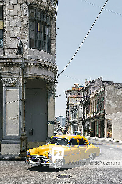 Cuba  Havana  Yellow vintage car driving along street in Centro Habana