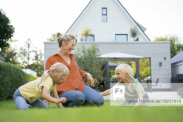 Glückliche Mutter  die mit Kindern im Garten spielt