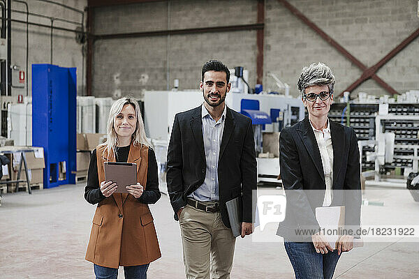 Happy businessman with colleagues standing in industry