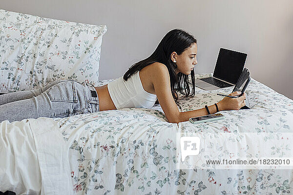 Mädchen benutzt Tablet-PC und liegt zu Hause im Bett