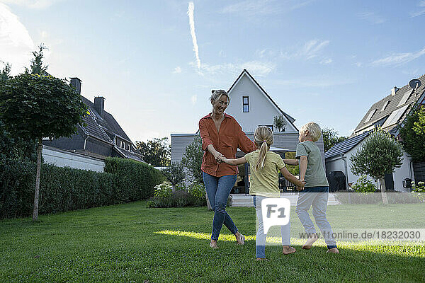 Playful mother playing ring around rosy with children in garden