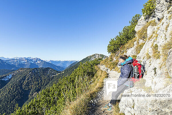 Germany  Bavaria  Female hiker taking break along footpath leading to summit of Heimgarten mountain