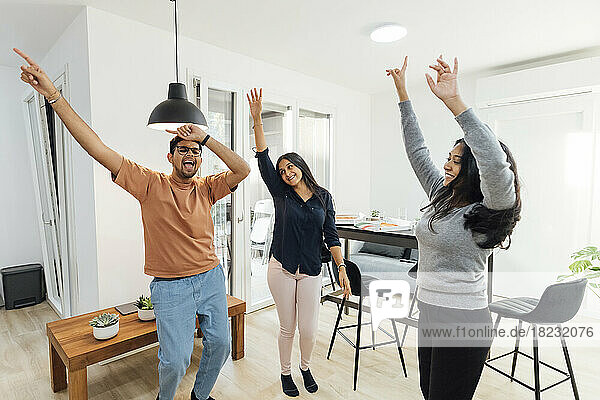 Happy women and man dancing in living room at home