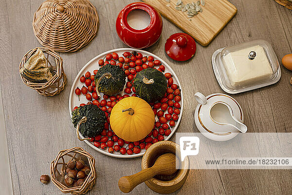 Pumpkins  rose hips  chestnuts  sugar bowl  mortal and pestle  milk jug and butter lying on wooden surface