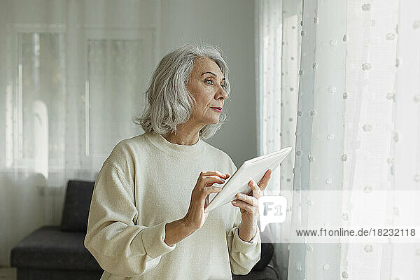 Senior woman holding digital tablet at home