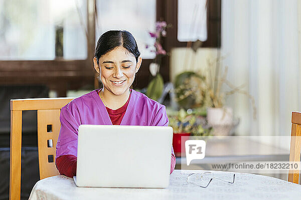 Smiling healthcare worker using laptop at home
