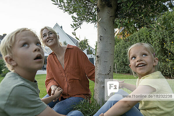 Smiling mother holding children's hands in back yard