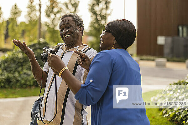Happy senior couple gesturing holding camera at park