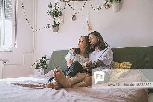 Nachdenkliches Hipster-Paar sitzt zu Hause im Bett