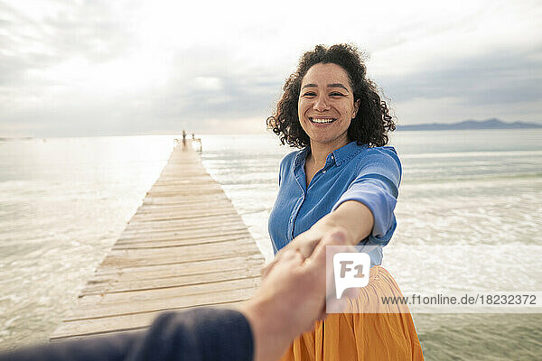 Happy woman holding hand of man on jetty
