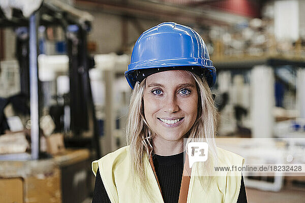 Happy young engineer wearing hardhat standing in industry