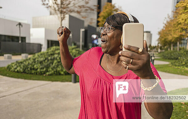 Happy woman holding smart phone enjoying at park