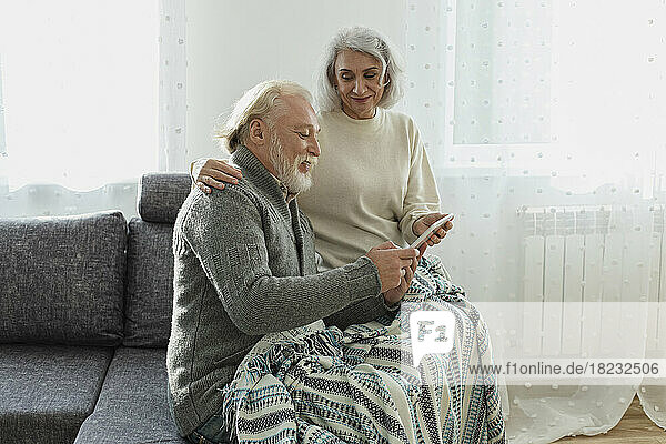 Senior couple sitting on couch with digital tablet