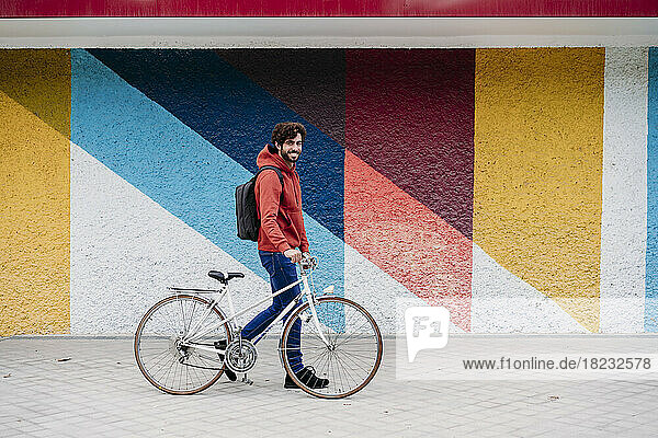 Mann fährt Fahrrad vor bunter Wand