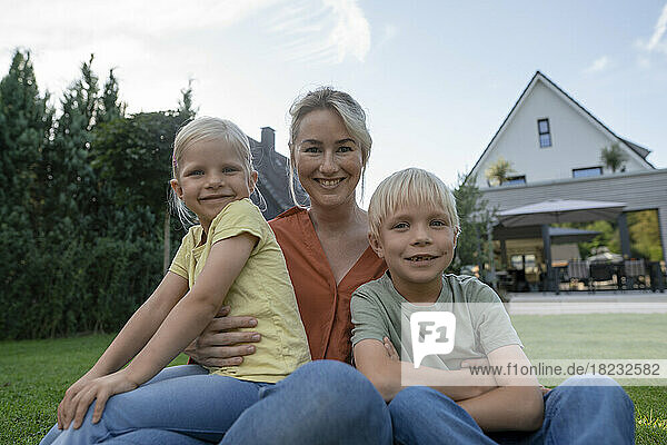 Smiling mother with son and daughter in back yard