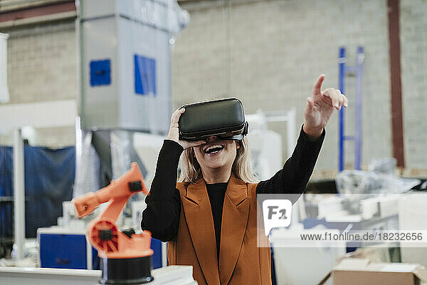 Happy businesswoman gesturing with virtual reality simulator at industry