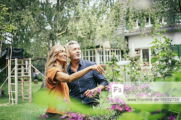 Happy man with woman gesturing in front of plants