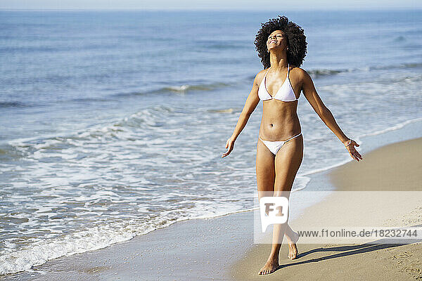 Carefree woman walking at beach on sunny day