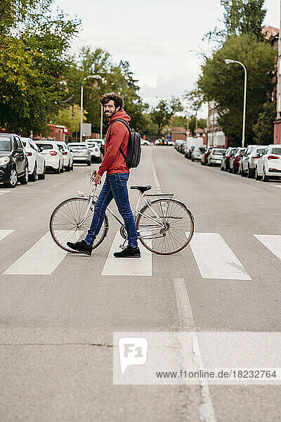 Man crossing road with bicycle in city