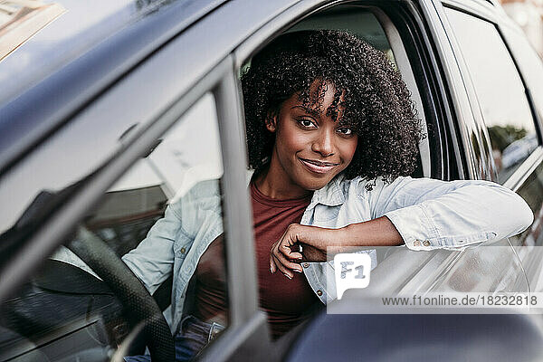 Smiling woman with curly hair sitting in car
