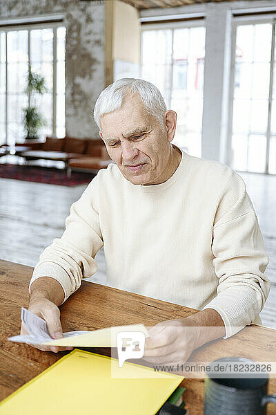 Senior man examining financial bills at home