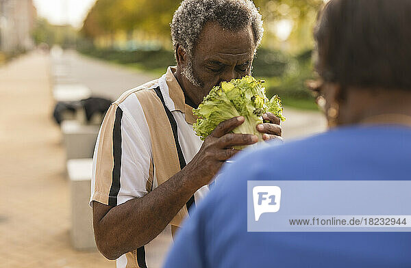 Man with eyes closed smelling fresh lettuce