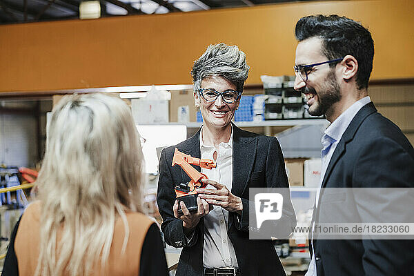 Happy mature businesswoman with robotic arm discussing with colleagues
