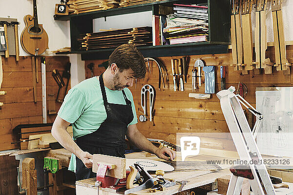 Guitar maker working on stencil of guitar in workshop