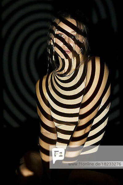 Junge Frau mit beleuchtetem Spiralmuster vor schwarzem Hintergrund