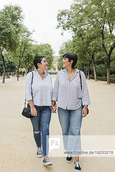 Lesbische Freundinnen gehen Händchen haltend im Park spazieren