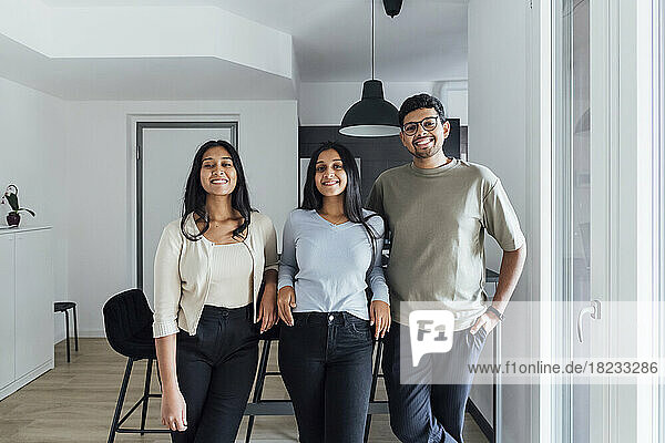 Smiling man standing by women in living room at home