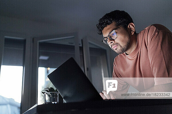Junger Mann benutzt Laptop auf Tisch zu Hause