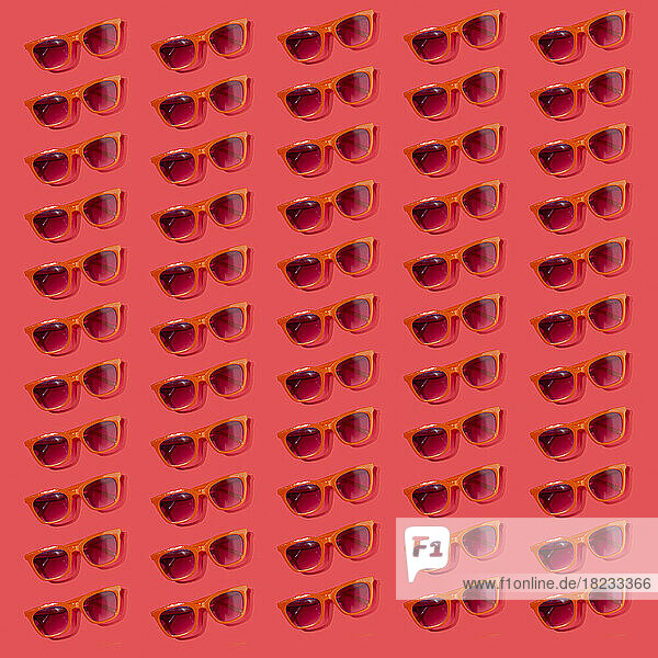 Pattern of old-fashioned sunglasses flat laid against red background