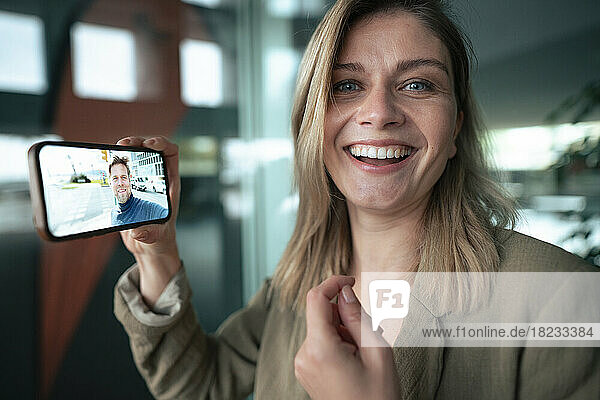 Lächelnde Geschäftsfrau bei Videoanruf mit Kollege über Smartphone