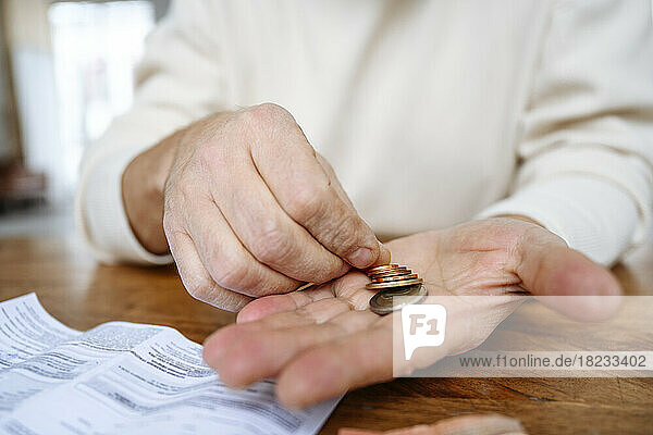 Man counting coins on hand at home