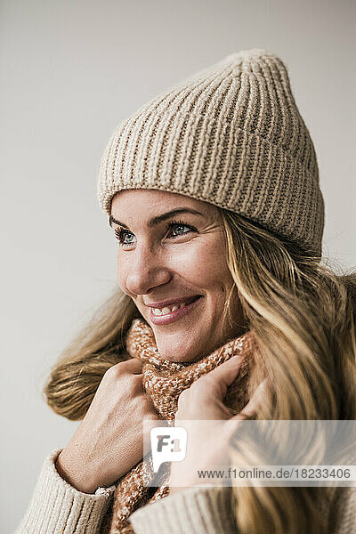 Happy blond woman wearing knit hat against white background