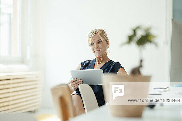 Reife Geschäftsfrau hält Tablet-PC im Büro