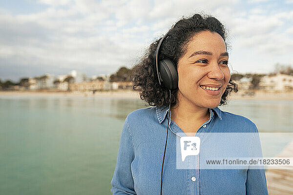 Glückliche Frau  die auf dem Seeweg mit Kopfhörern Musik hört