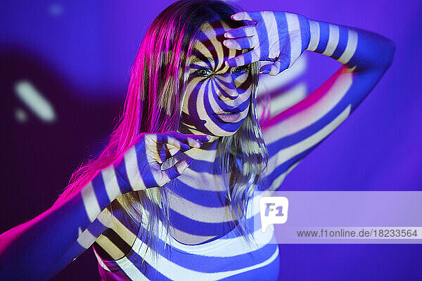 Young woman with illuminated swirl pattern in front of wall