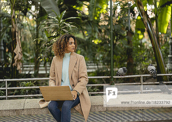 Businesswoman with laptop on bench