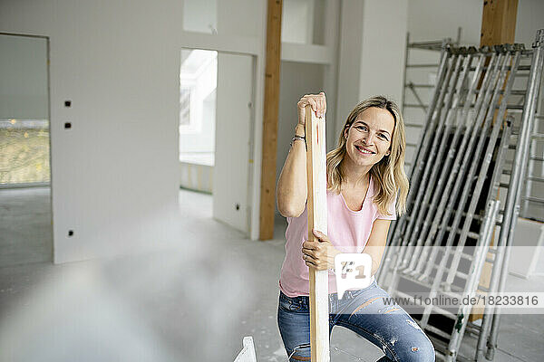 Happy woman holding wooden plank in apartment