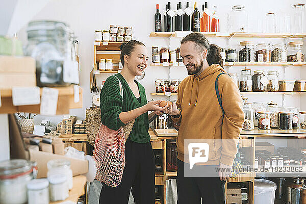 Smiling man and woman holding eggs in zero waste shop