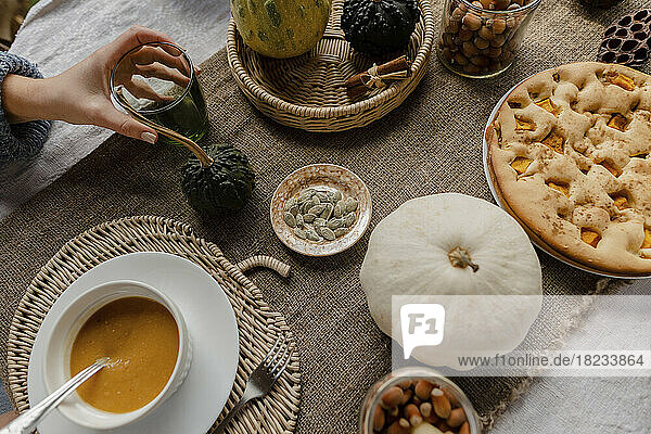 Hand of woman eating pumpkin porridge at autumnal table