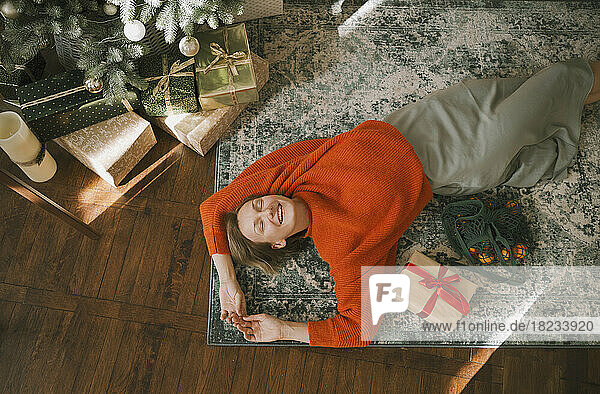 Smiling woman lying down on carpet at home
