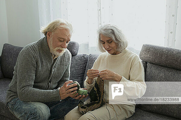 Senior couple sitting on couch knitting