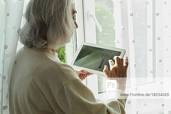 Senior woman adjusting temperature on smart home device
